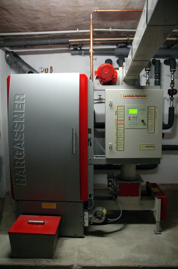Hackschnitzelkessel von Hargassner mit Regelung Lambda-Hatronic und Ascheschublade in einem Heizungskeller